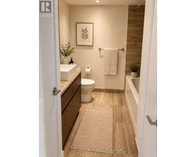 A bathroom with a toilet, sink, and a rug on the floor.