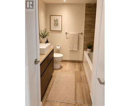 A bathroom with a toilet, sink, and a rug on the floor.