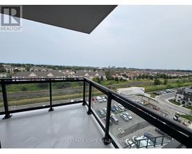 A balcony with a view of a parking lot and buildings.