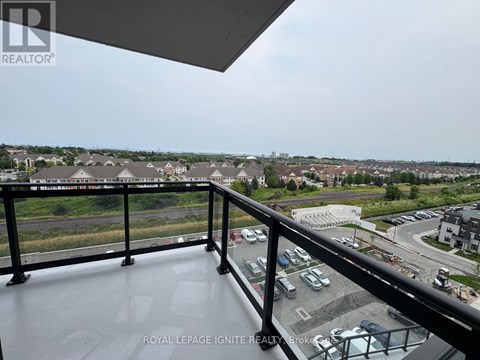 A balcony with a view of a parking lot and buildings.