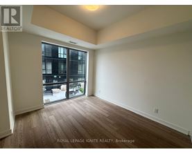A room with wooden flooring and a sliding glass door leading to a balcony.