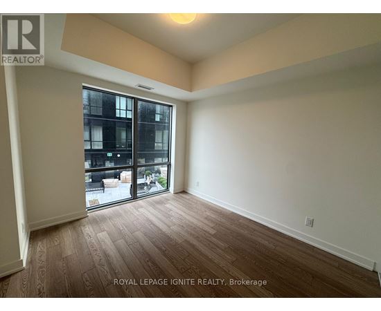 A room with wooden flooring and a sliding glass door leading to a balcony.