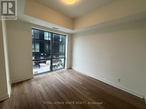 A room with wooden flooring and a sliding glass door leading to a balcony.