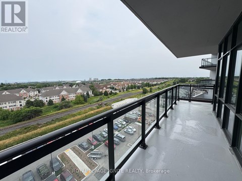 A balcony with a view of a parking lot and buildings.