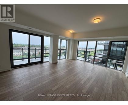 A spacious room with wooden flooring and large windows overlooking a cityscape.