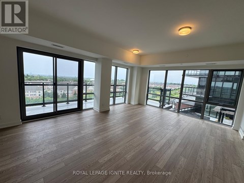 A spacious room with wooden flooring and large windows overlooking a cityscape.