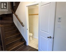 A white door is open to a bathroom with a toilet and a wooden staircase.