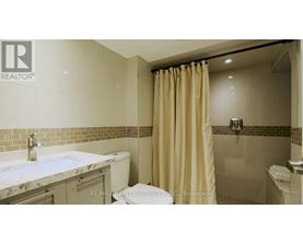 A bathroom with a marble countertop and beige shower curtain.
