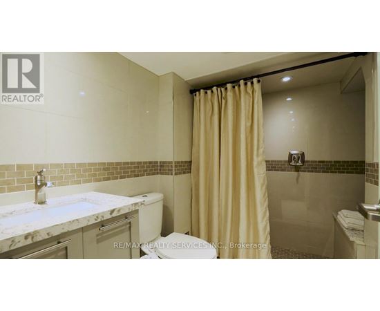A bathroom with a marble countertop and beige shower curtain.