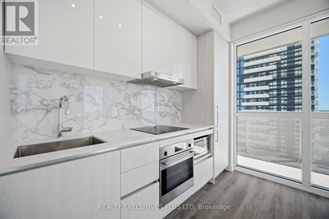 A modern kitchen with white cabinets and a marble backsplash.