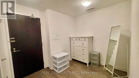 A bedroom with a white dresser and a black door.