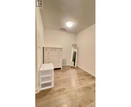 A white dresser with a white cabinet and a white chair in a room with wooden flooring.