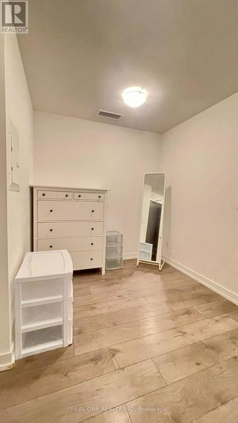 A white dresser with a white cabinet and a white chair in a room with wooden flooring.