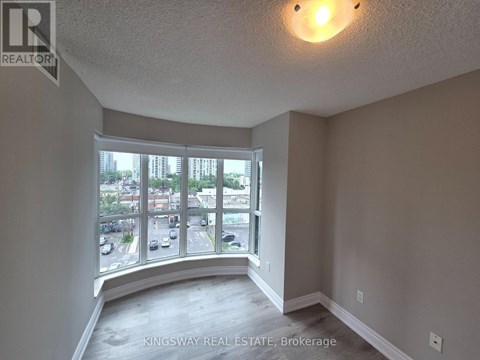 A real estate brokerage image of an empty room with a view of a parking lot and buildings outside.