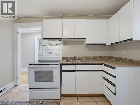 A kitchen with white cabinets and a stove top oven.