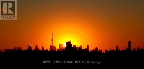 A city skyline at sunset with the sun partially obscured by buildings.