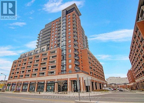 A tall red brick building with a glass facade on the top floors is the main focus of the image.
