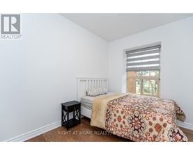 A bedroom with a bed, a small table, and a window with blinds.