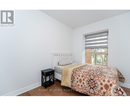 A bedroom with a bed, a small table, and a window with blinds.