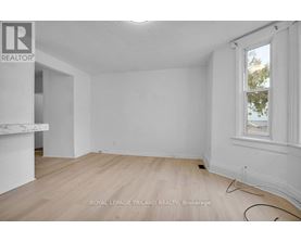 A white room with a window and wooden flooring.
