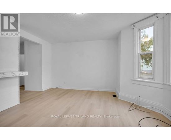 A white room with a window and wooden flooring.