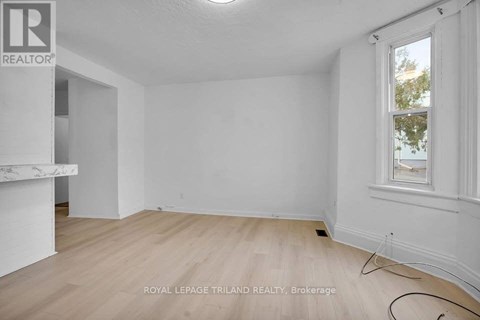 A white room with a window and wooden flooring.