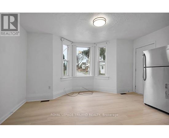 A white room with a window and a refrigerator.