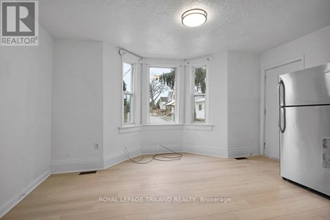 A white room with a window and a refrigerator.