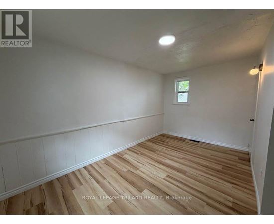 A room with wooden flooring and white walls.