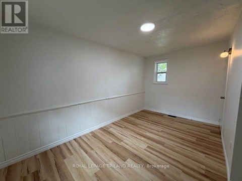 A room with wooden flooring and white walls.