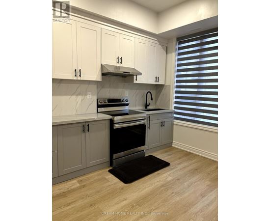 A kitchen with white cabinets and a black mat on the floor.