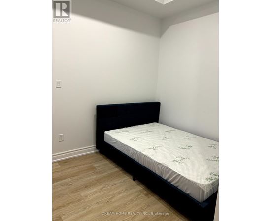 A bed with a black headboard and a white mattress is in a room with white walls.