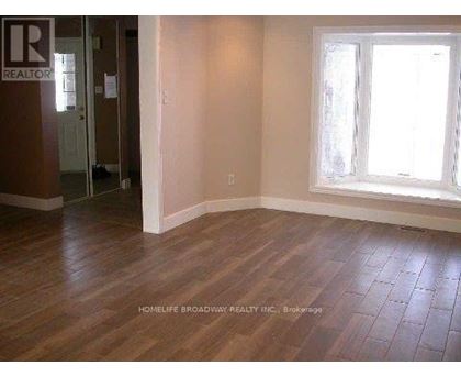 A room with wooden flooring and a window letting in sunlight.