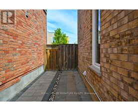 A narrow alleyway between two brick buildings with a wooden gate at the end.