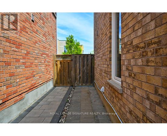 A narrow alleyway between two brick buildings with a wooden gate at the end.