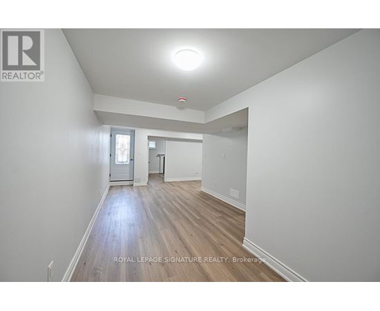 A spacious room with wooden flooring and white walls.