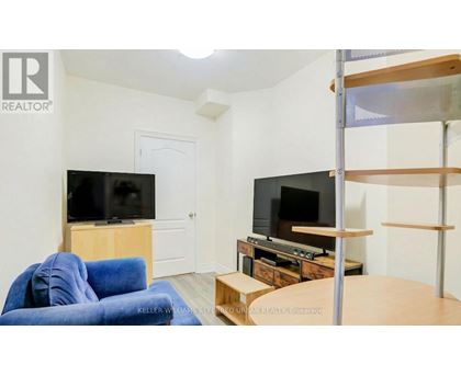 A living room with a blue couch and two TVs.