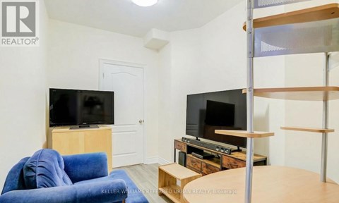 A living room with a blue couch and two TVs.
