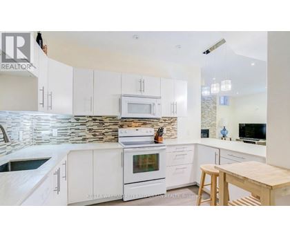 A kitchen with white cabinets and a stone backsplash.