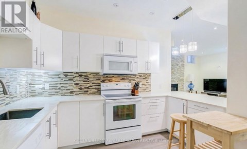 A kitchen with white cabinets and a stone backsplash.