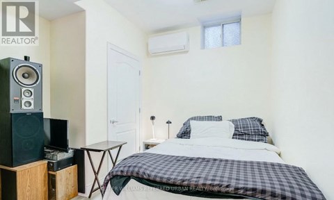 A bedroom with a bed, a table, and a speaker.