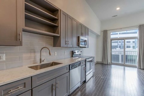 A modern kitchen with dark wood floors and a stainless steel sink.