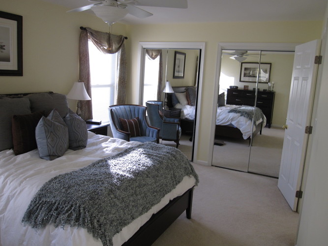 A bedroom with a large bed and a mirrored closet door.