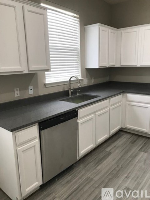 A kitchen with white cabinets and a black countertop.
