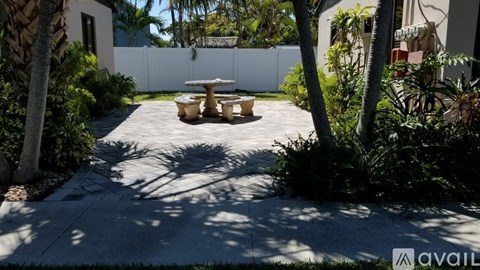 A patio with a table and chairs surrounded by green plants.