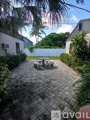 A patio with a table and chairs surrounded by greenery.