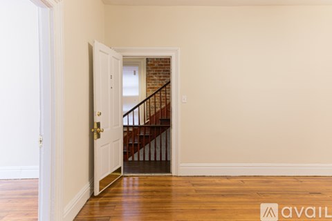 A hallway with a wooden staircase and a white door.