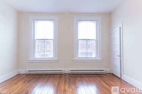 A room with wooden floors and two windows.