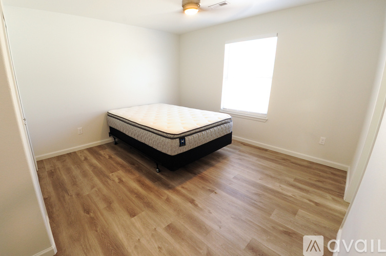 A bedroom with a bed, wooden floors, and a window.