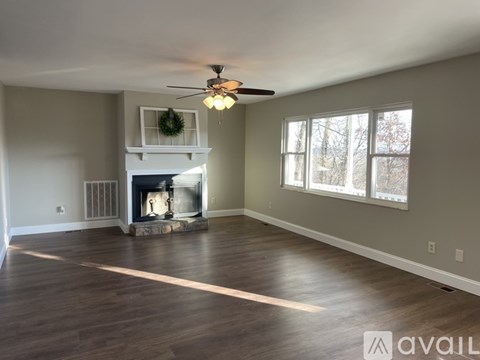 A spacious living room with a fireplace and a ceiling fan.